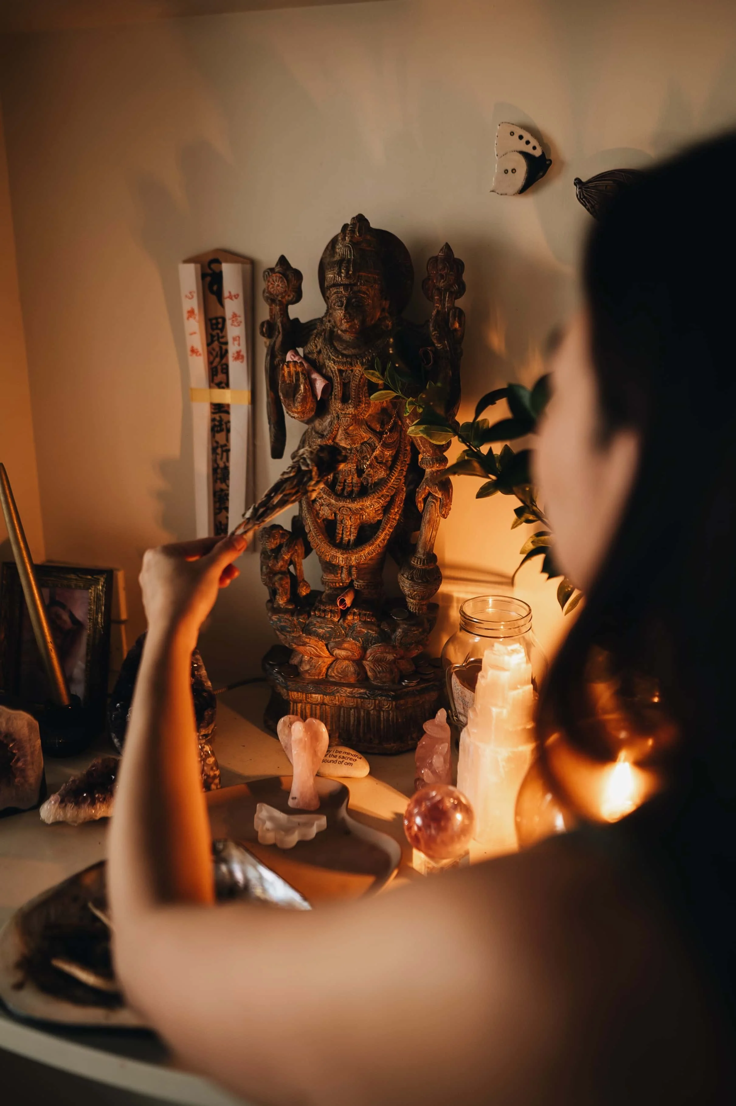 a woman burning sage in front of an altar