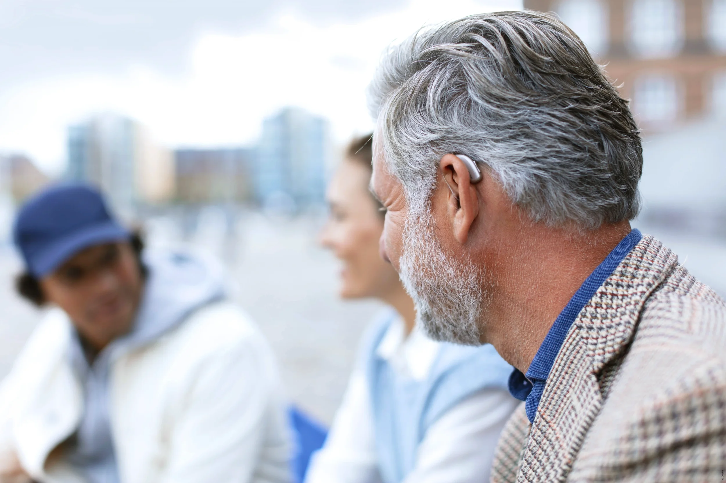 A man wearing hearing aids sat outdoors with friends