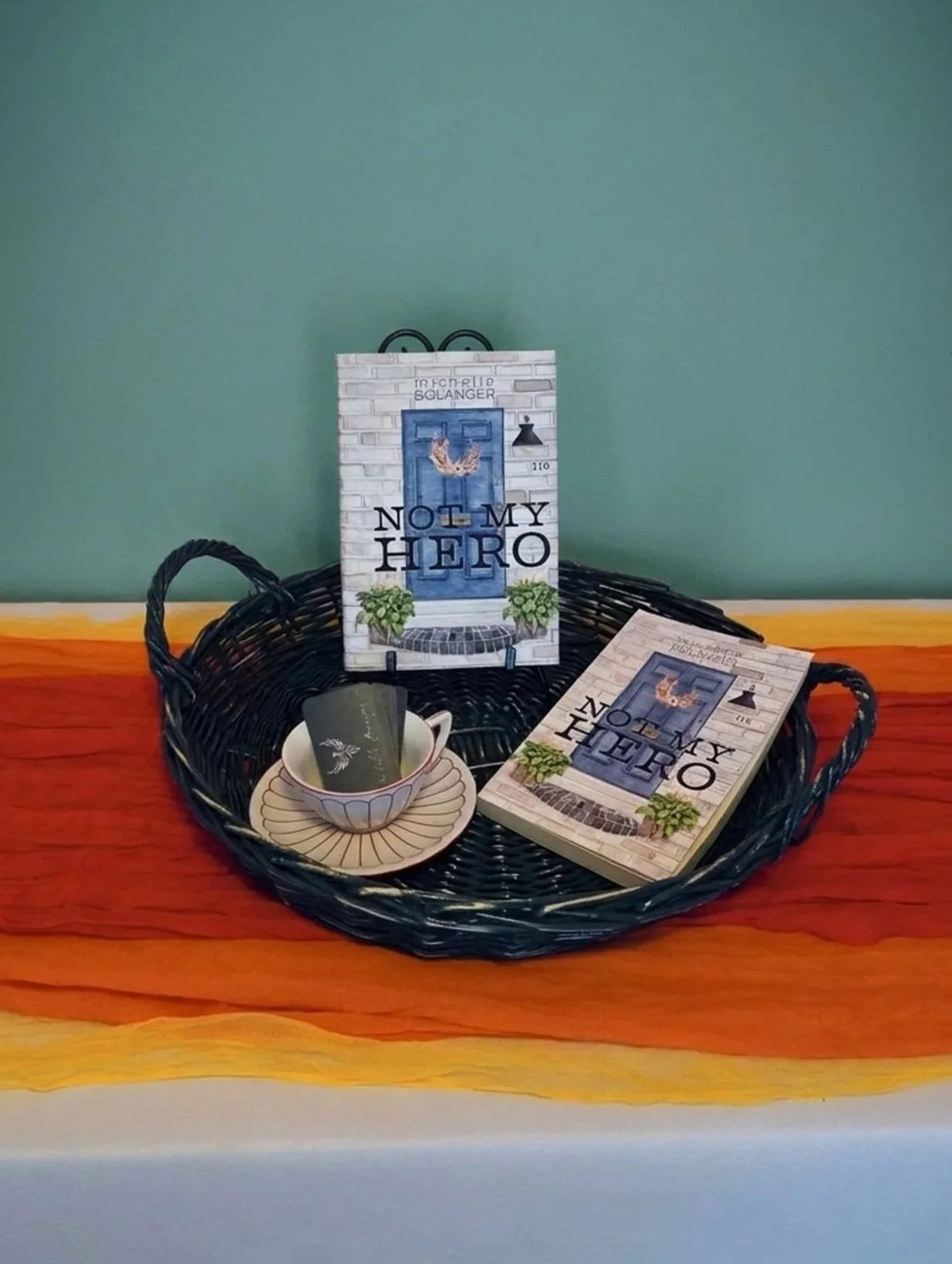 Two books in a basket with a saucer and teacup filled with business cards