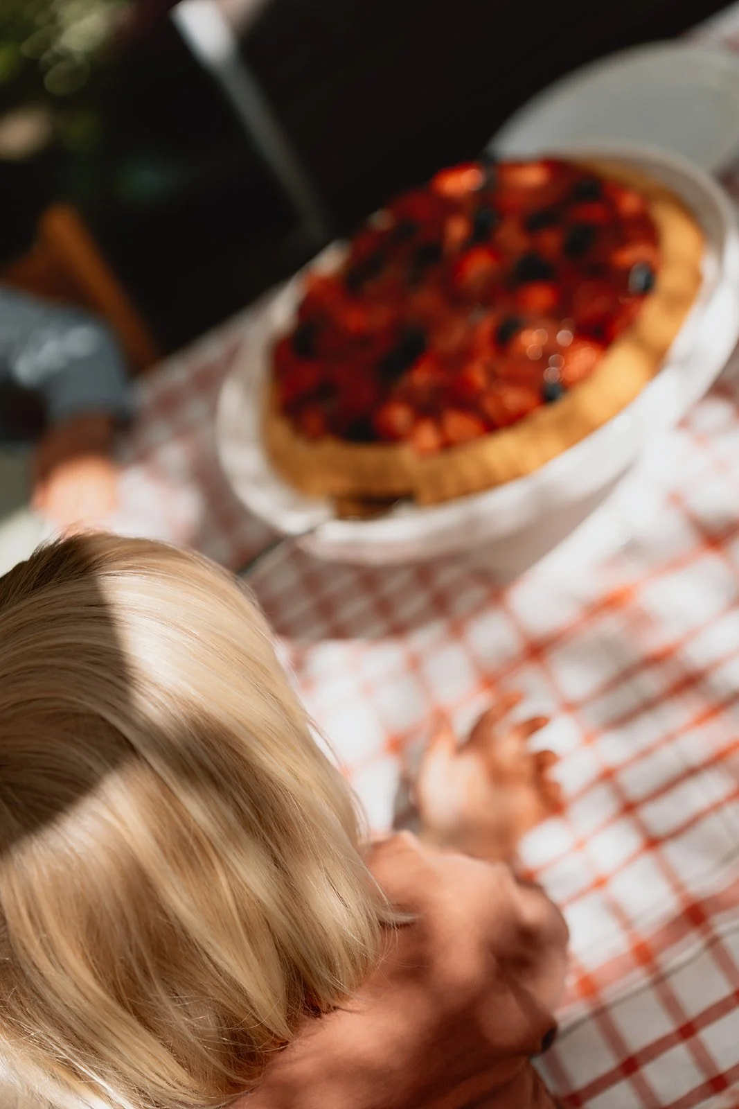 Eine Gruppe von Menschen sitzt an einem Tisch, auf dem eine Obstkuchen mit Beeren ist.