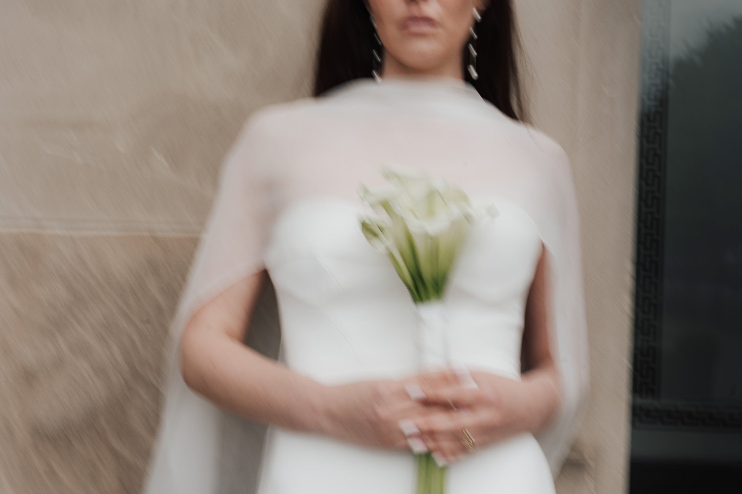 Verrauschtes Foto einer Frau in einem weißen Kleid, die einen Blumenstrauß hält.