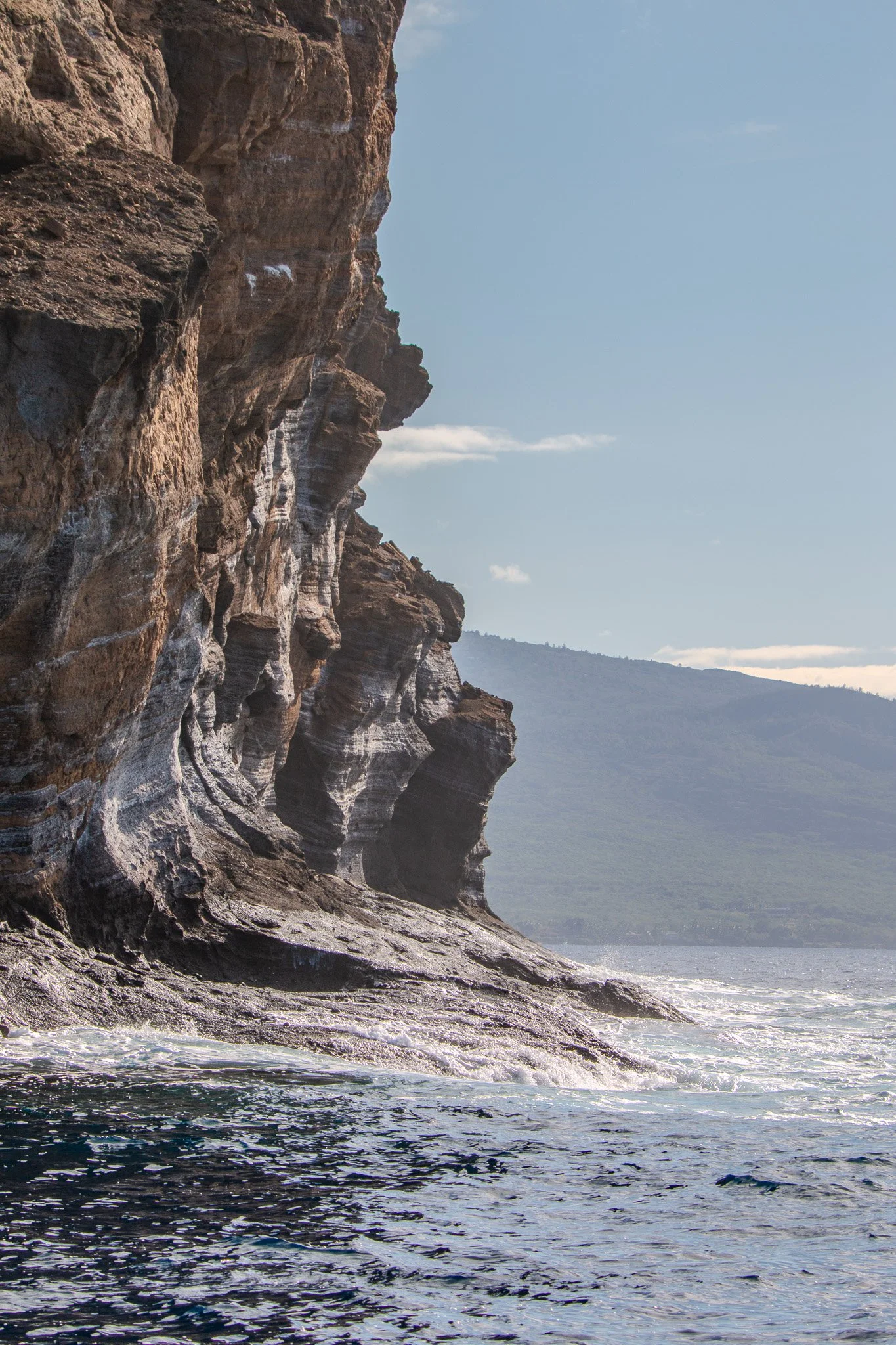 Volcanic cliff and lava shelf on the backside of Molokini Crater with Maui’s Makena coastline in the distance