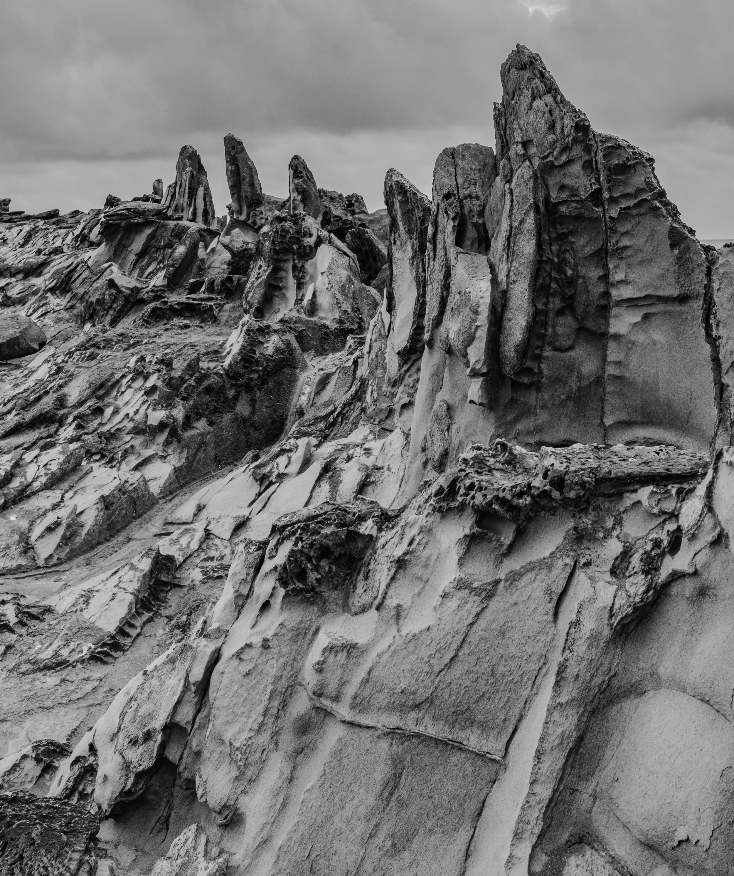 Black and white Dragon’s Teeth lava formations in Kapalua Maui showing jagged volcanic rock along the coastline