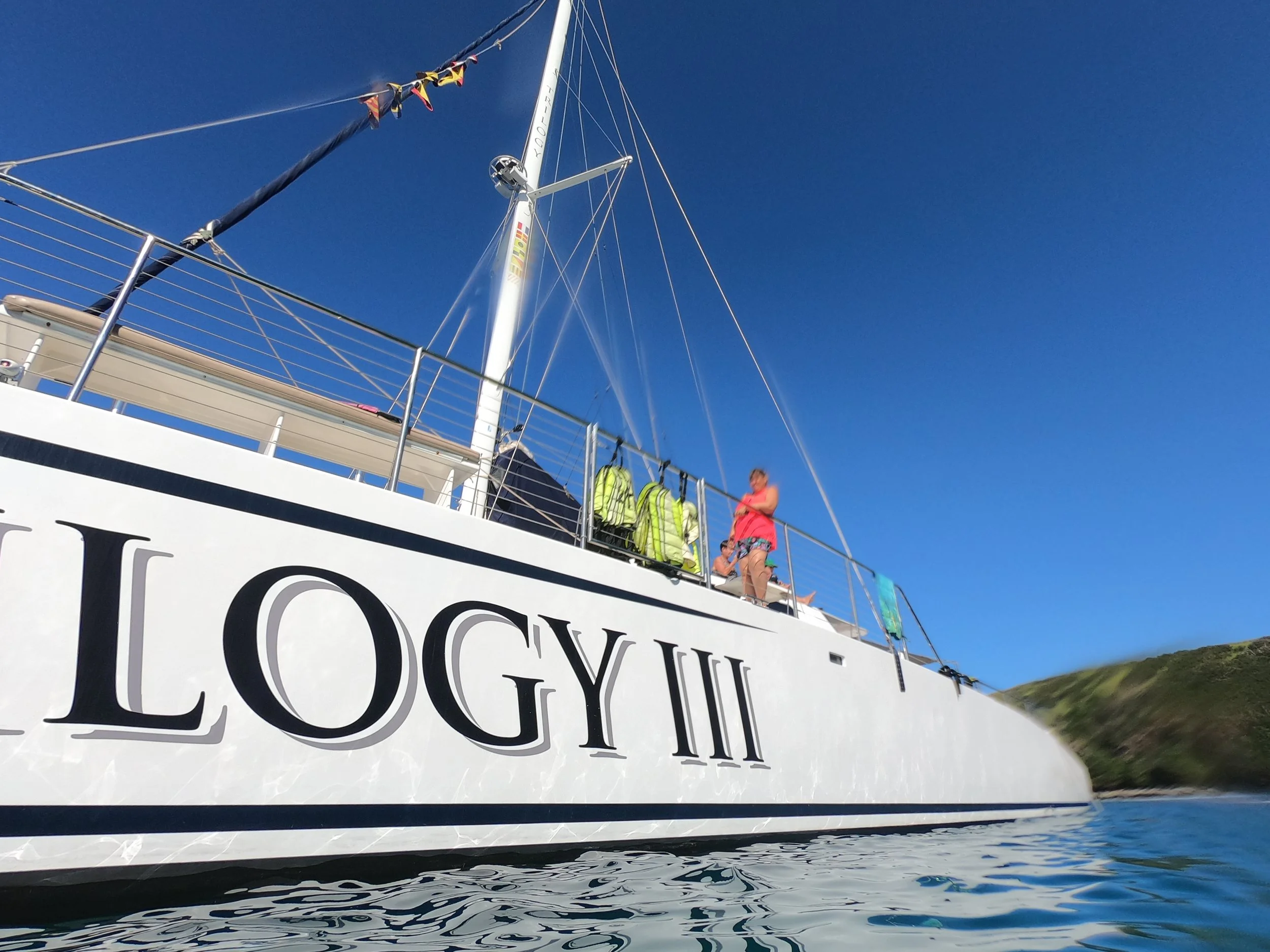 Trilogy III catamaran anchored in Honolua Bay on Maui's northwest coast with clear Pacific waters and lush shoreline.