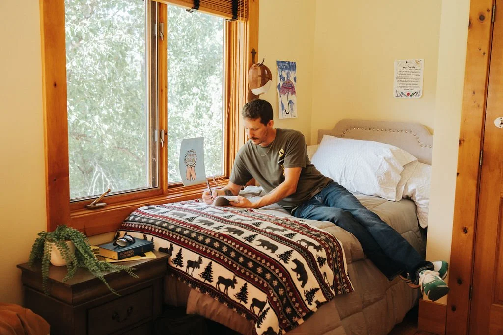 Shared bedroom space with warm natural light and wood finishes.