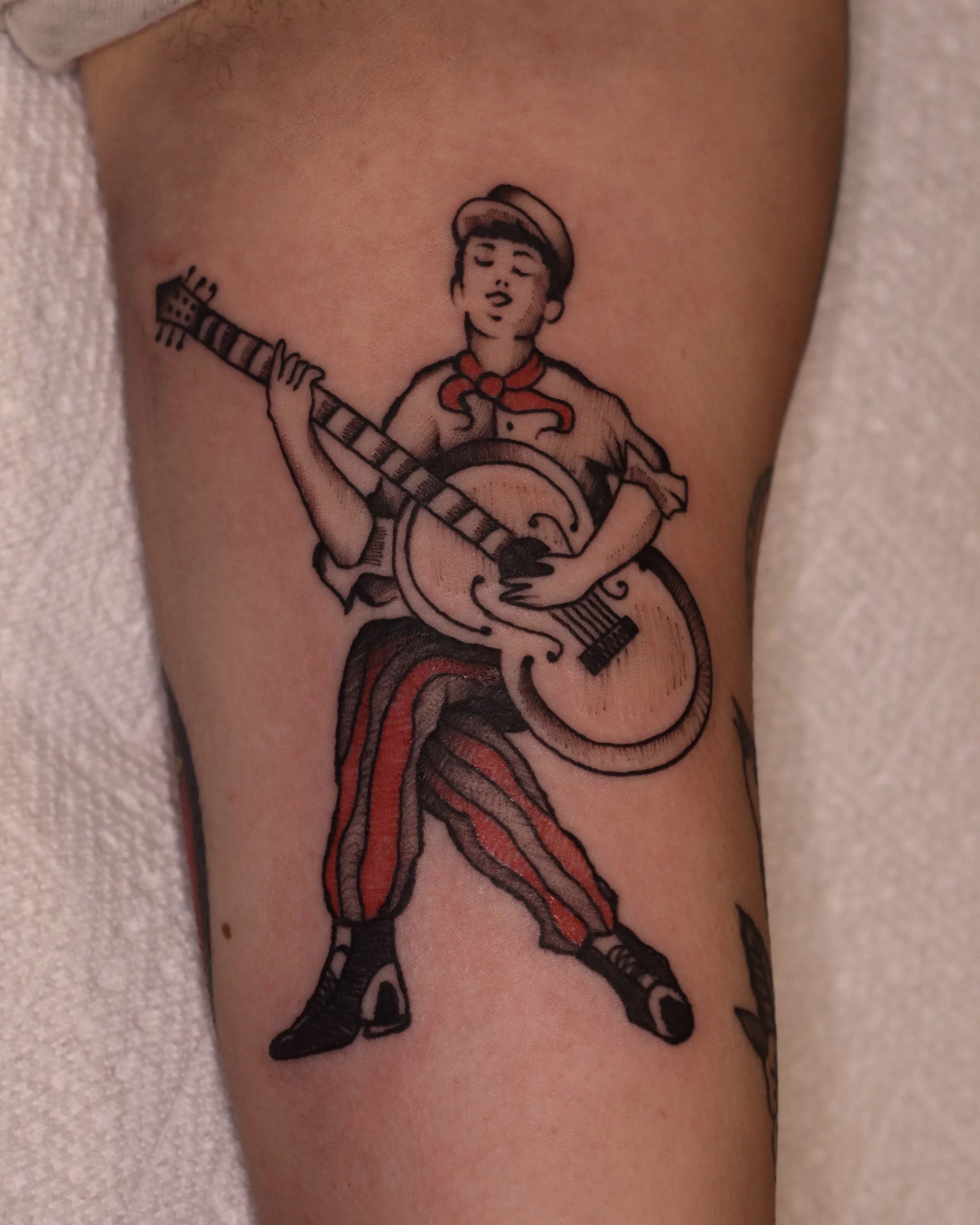 Tattoo of a man playing a guitar and singing