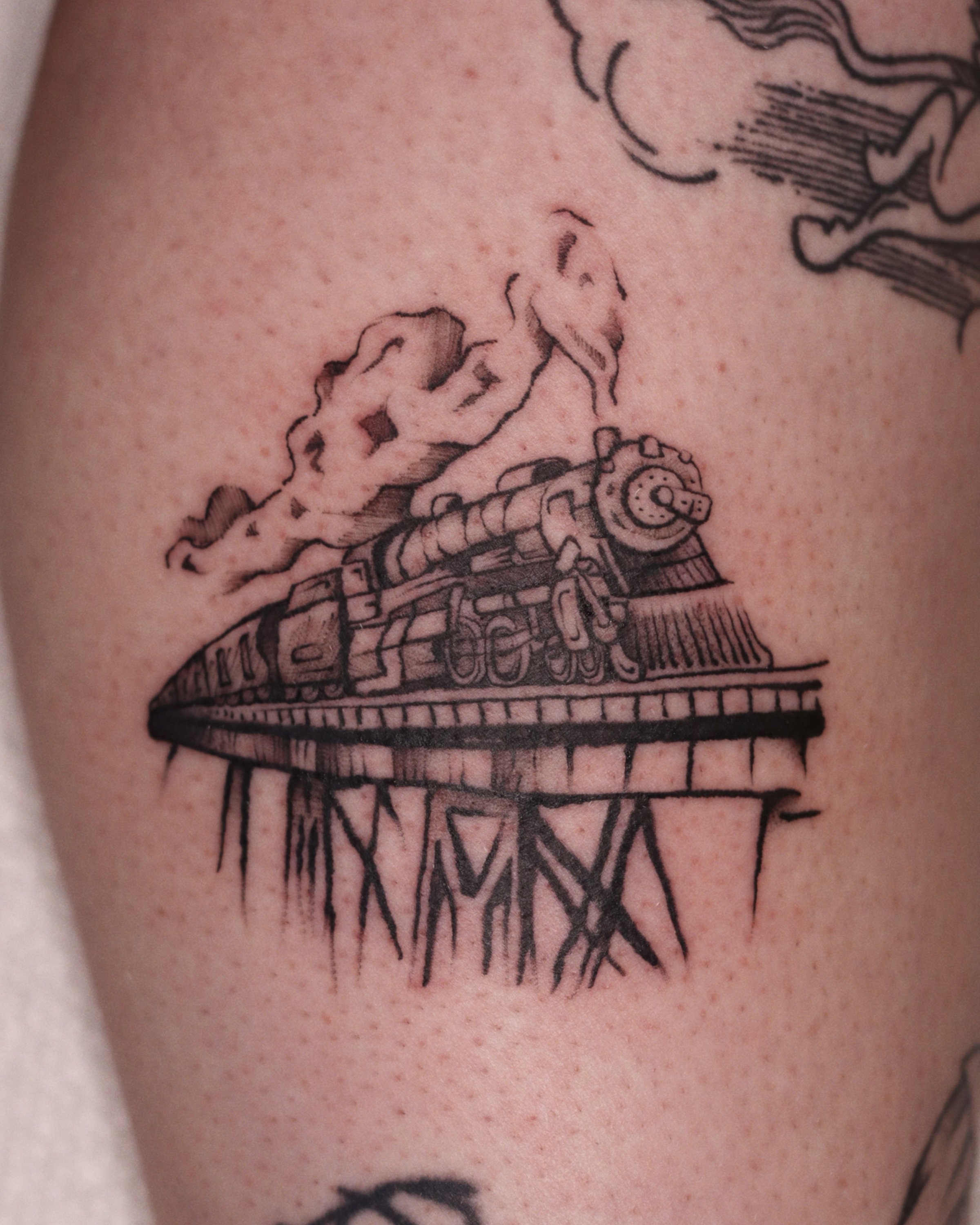 Rustic tattoo of a train on tracks 