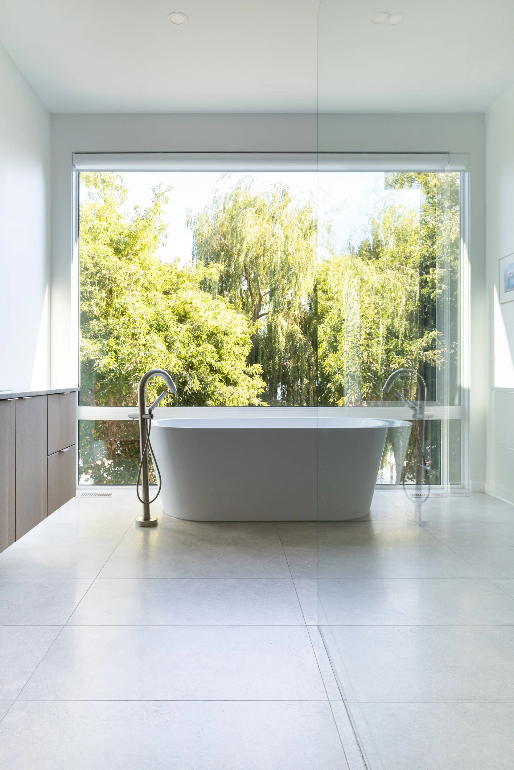 Primary ensuite bathtub in a custom home built in Vernon, BC, with willow trees out the window