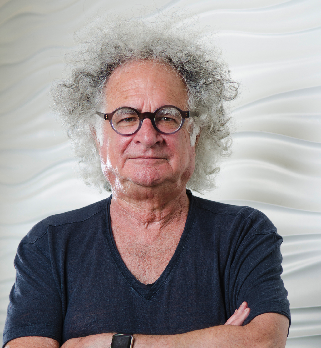 Black and white photo of a young woman with long dark hair, smiling slightly with arms crossed, wearing a dark sweatshirt and a smartwatch.