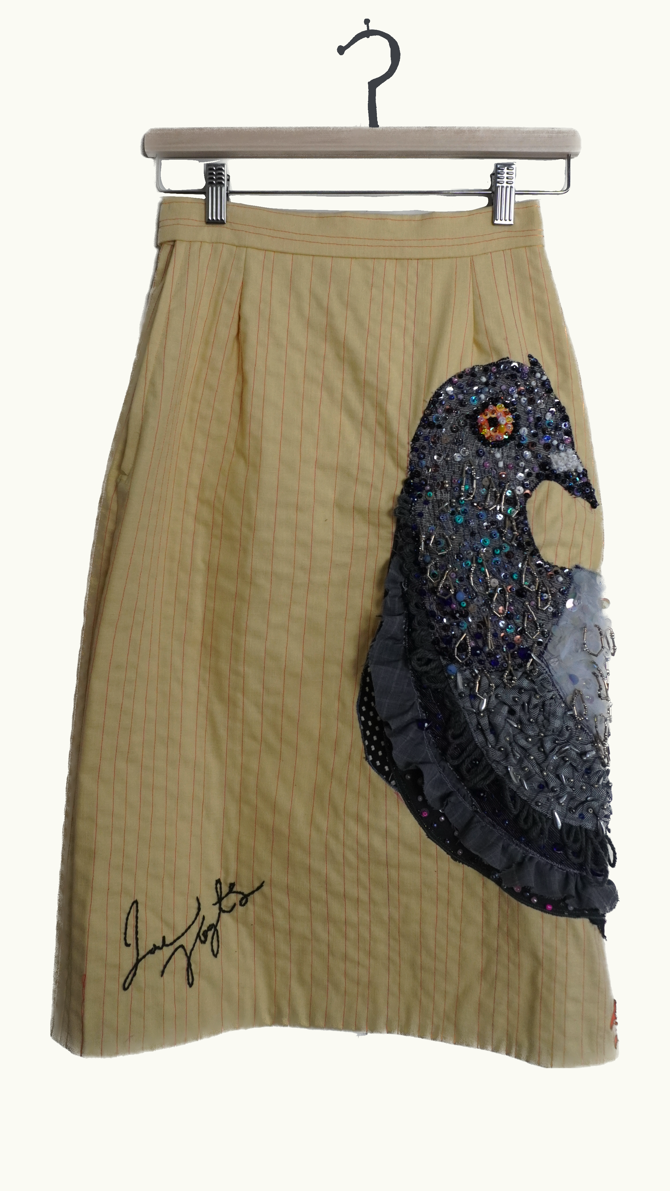 Yellow striped skirt with a large decorated black and silver sequin and bead embroidery design along the side and a signature at the bottom.