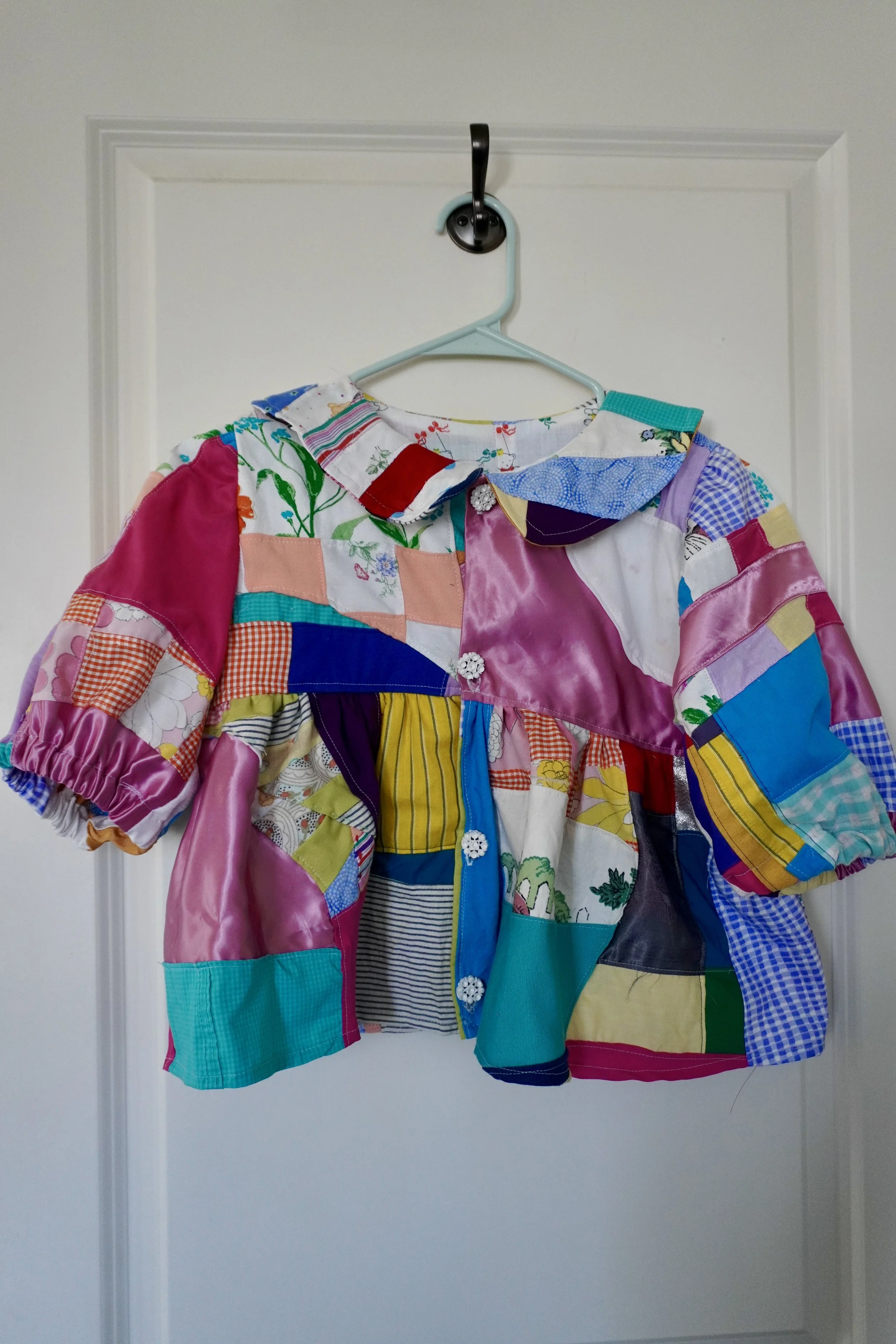 Colorful patchwork jacket hanging on a door hook.