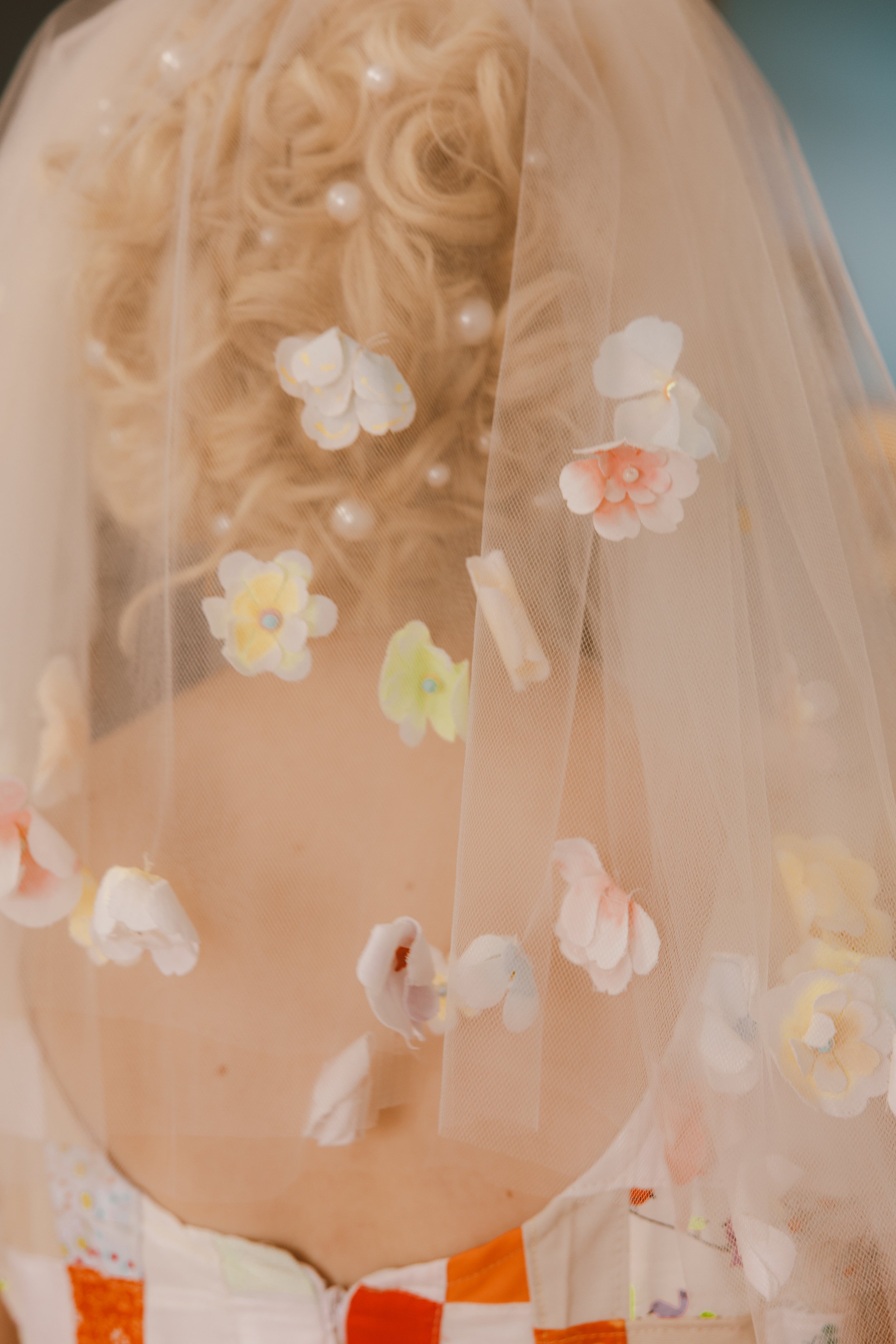 Close-up of a person's face partially hidden behind a sheer veil with floral and pearl decorations.