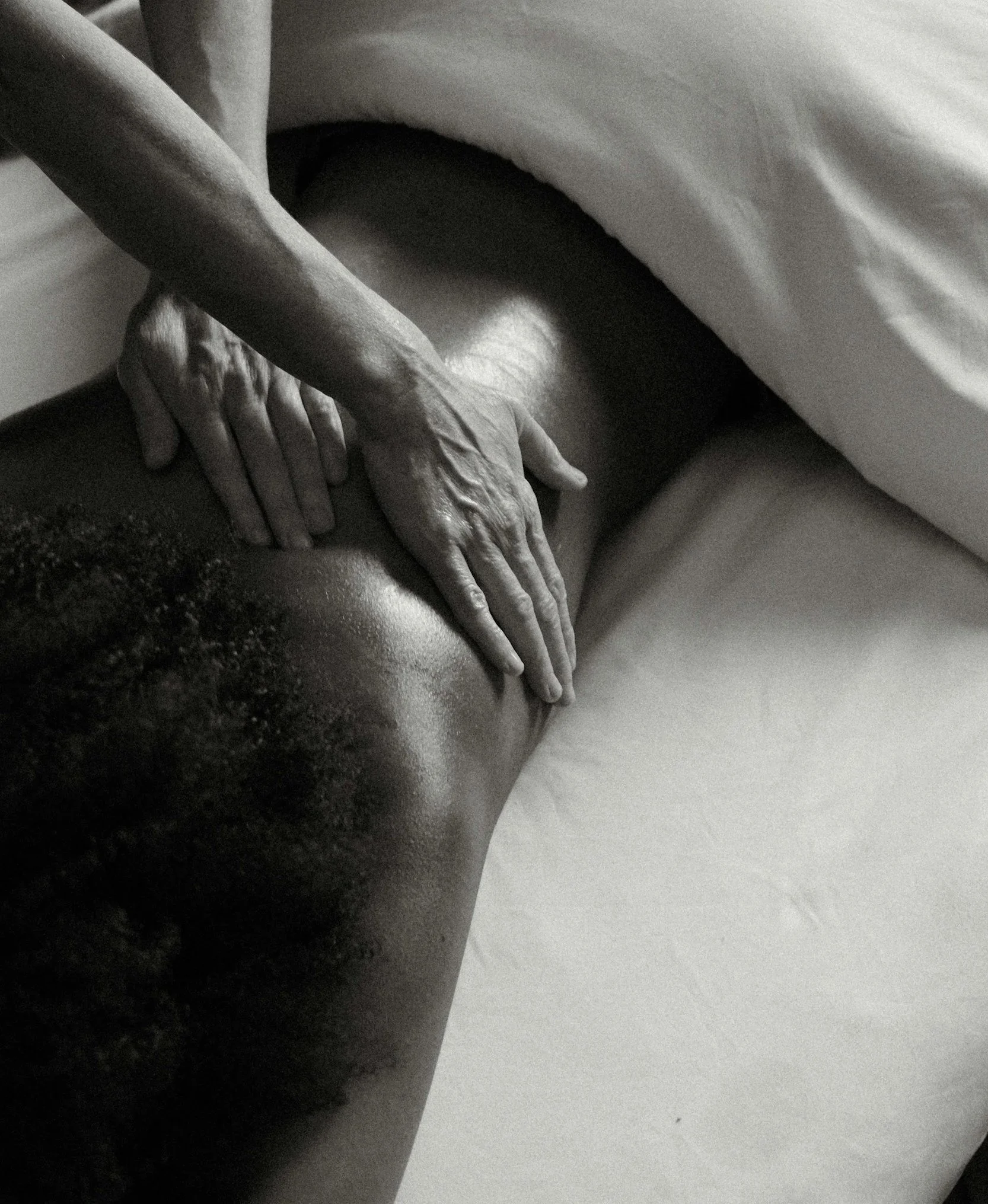 Close-up of hands giving a massage on a person's back in black and white.
