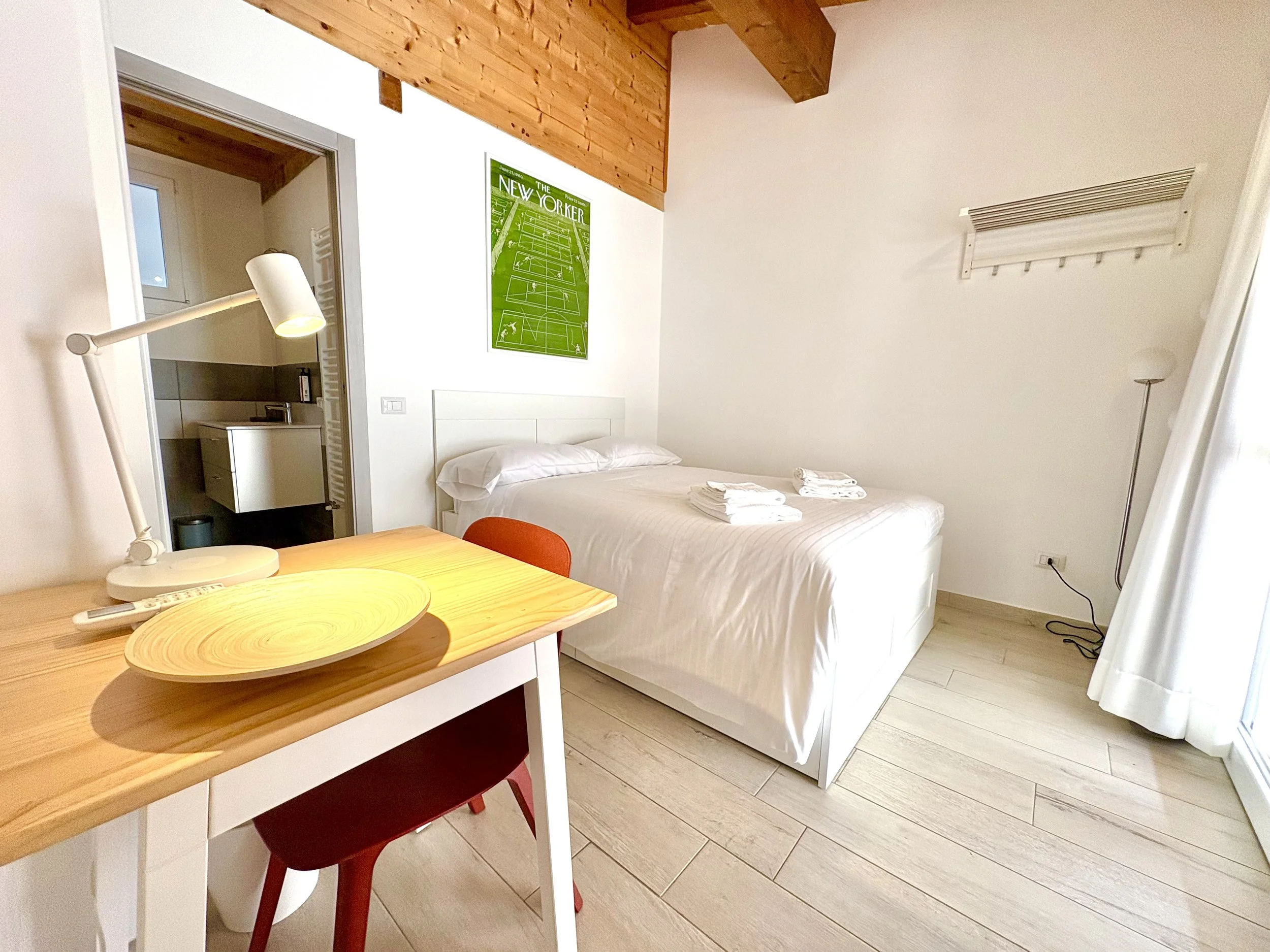 Cozy guest room at The Club House in Bordighera with double bed, high ceiling, and desk area.