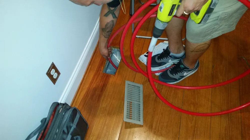 Air Duct Pros technician using professional agitation equipment in a floor supply duct