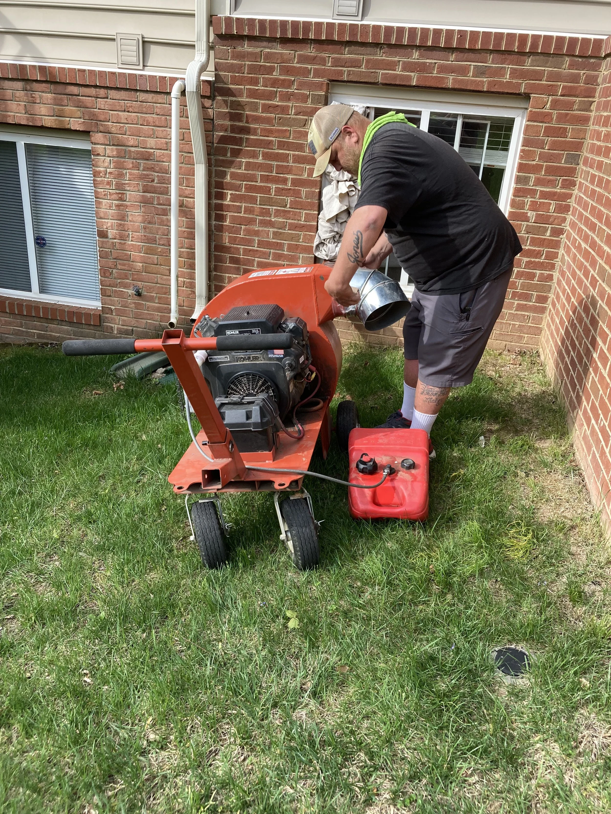 HP20 machine on a grassy backyard, connected to a gas can, with garden tools and greenery nearby.