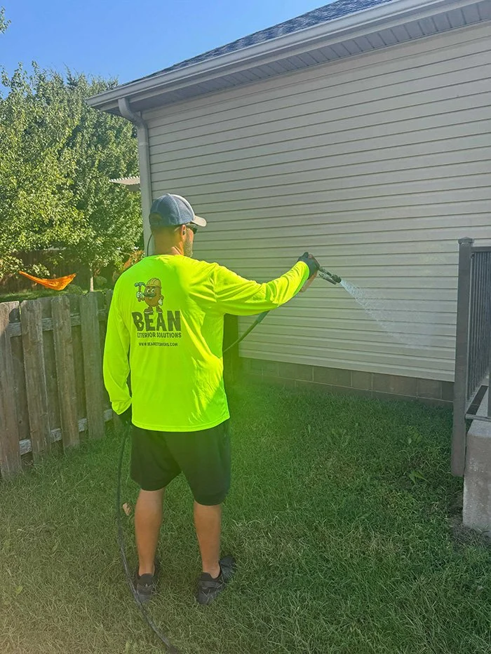 Bean crew member power washing a home's siding