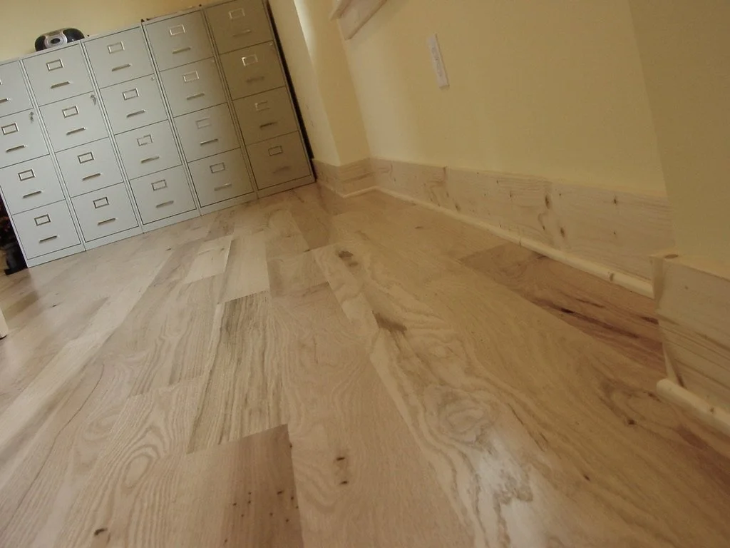 White oak sand and finish floor and custom milled spruce baseboard and shoe molding.