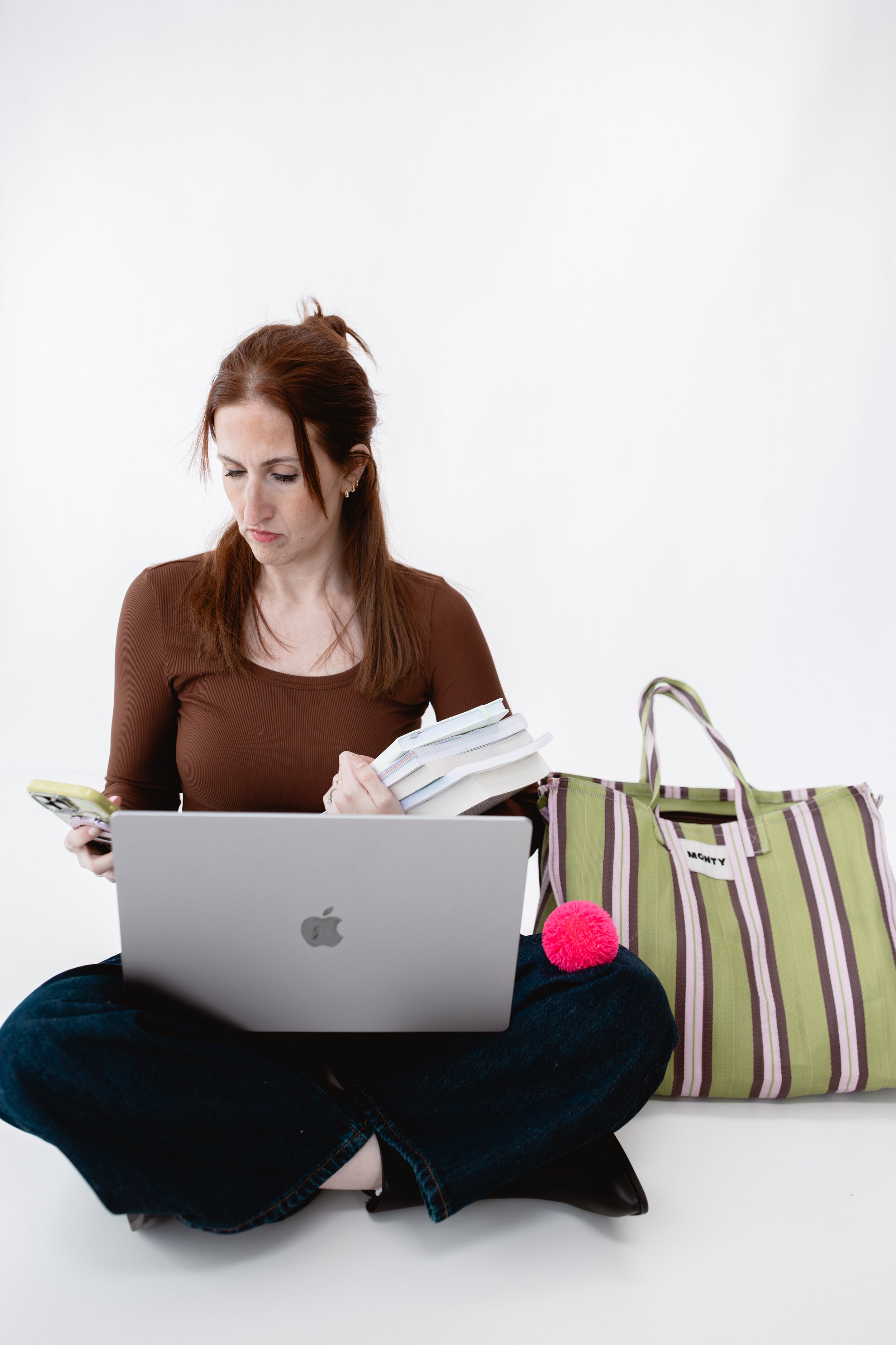 ADHD therapist Samantha Skvaril seated on the floor with laptop, books, and phone, symbolizing real-life, neurodivergent-affirming therapy for adults.