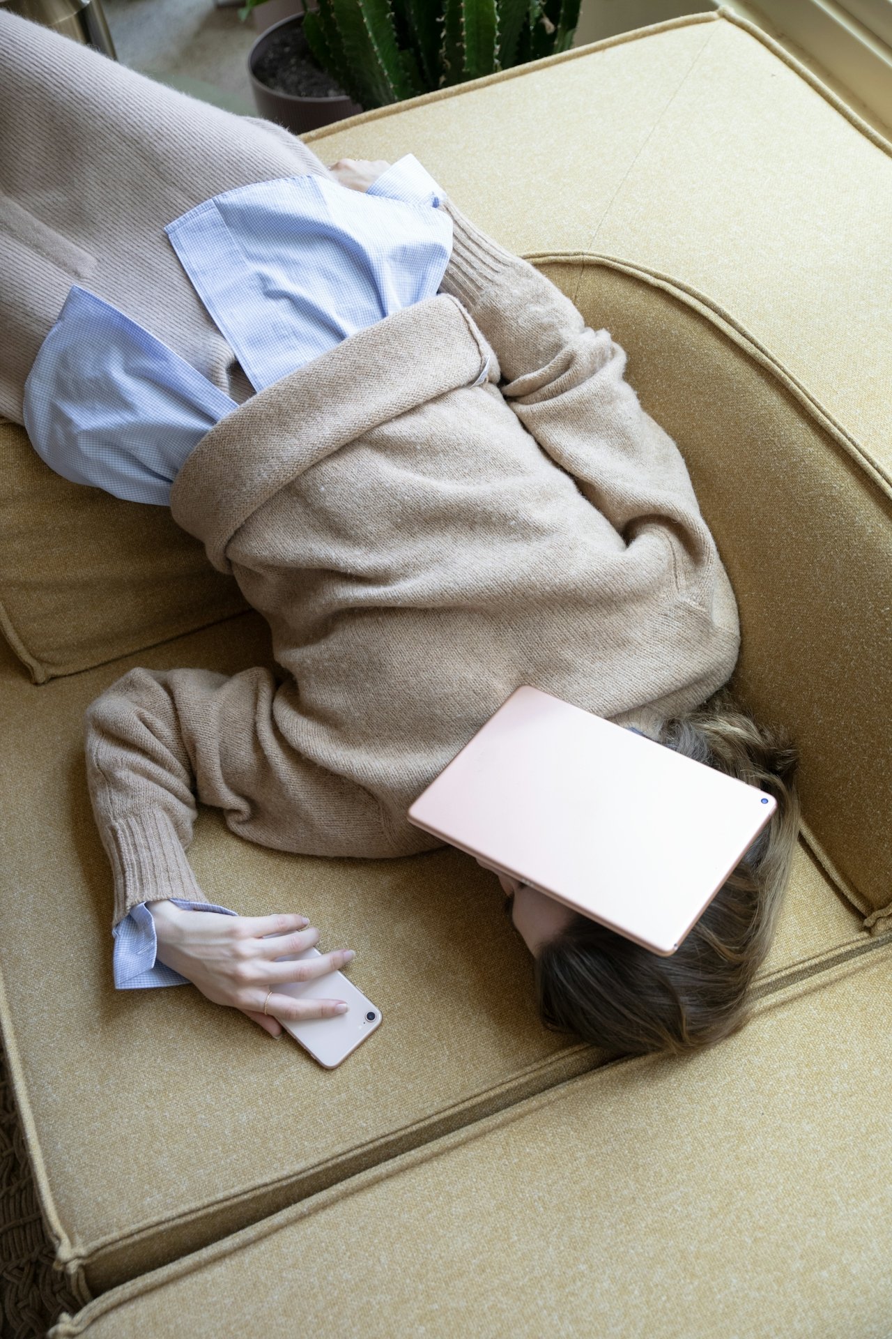 A woman on a couch with her phone and iPad, symbolizing the burnout and overwhelm common for late-diagnosed millennials seeking ADHD therapy in Illinois.