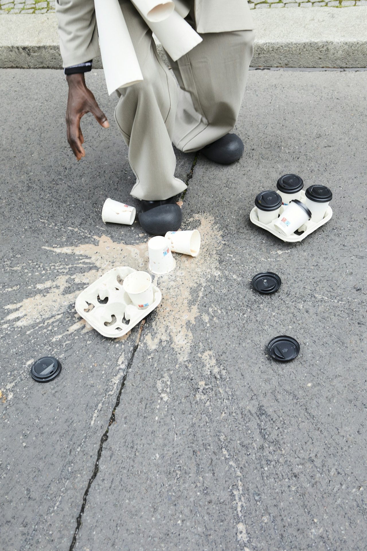 spilled takeout coffee cups scattered on a street next to a pothole
