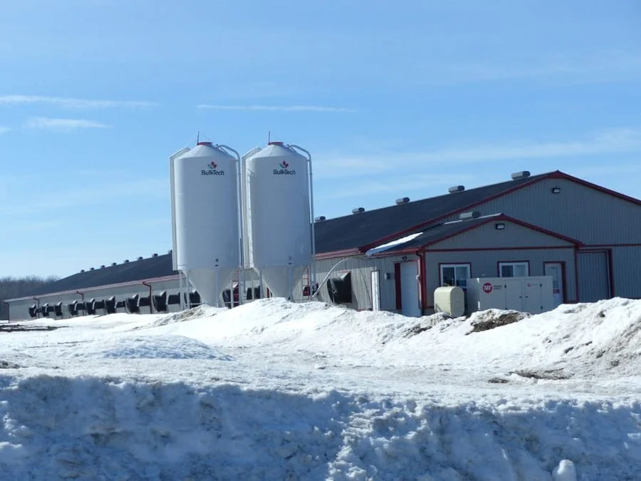 Snow-covered industrial building with three large silos labeled 'BulkTech' and various equipment outside.