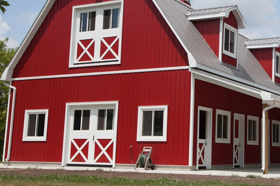 Red barn-style building with white trim, multiple windows, and a metal gable roof.