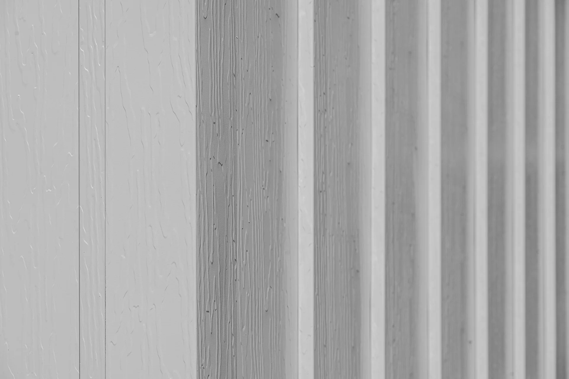 Close-up of a textured, partly wet, metallic wall with vertical ridges.