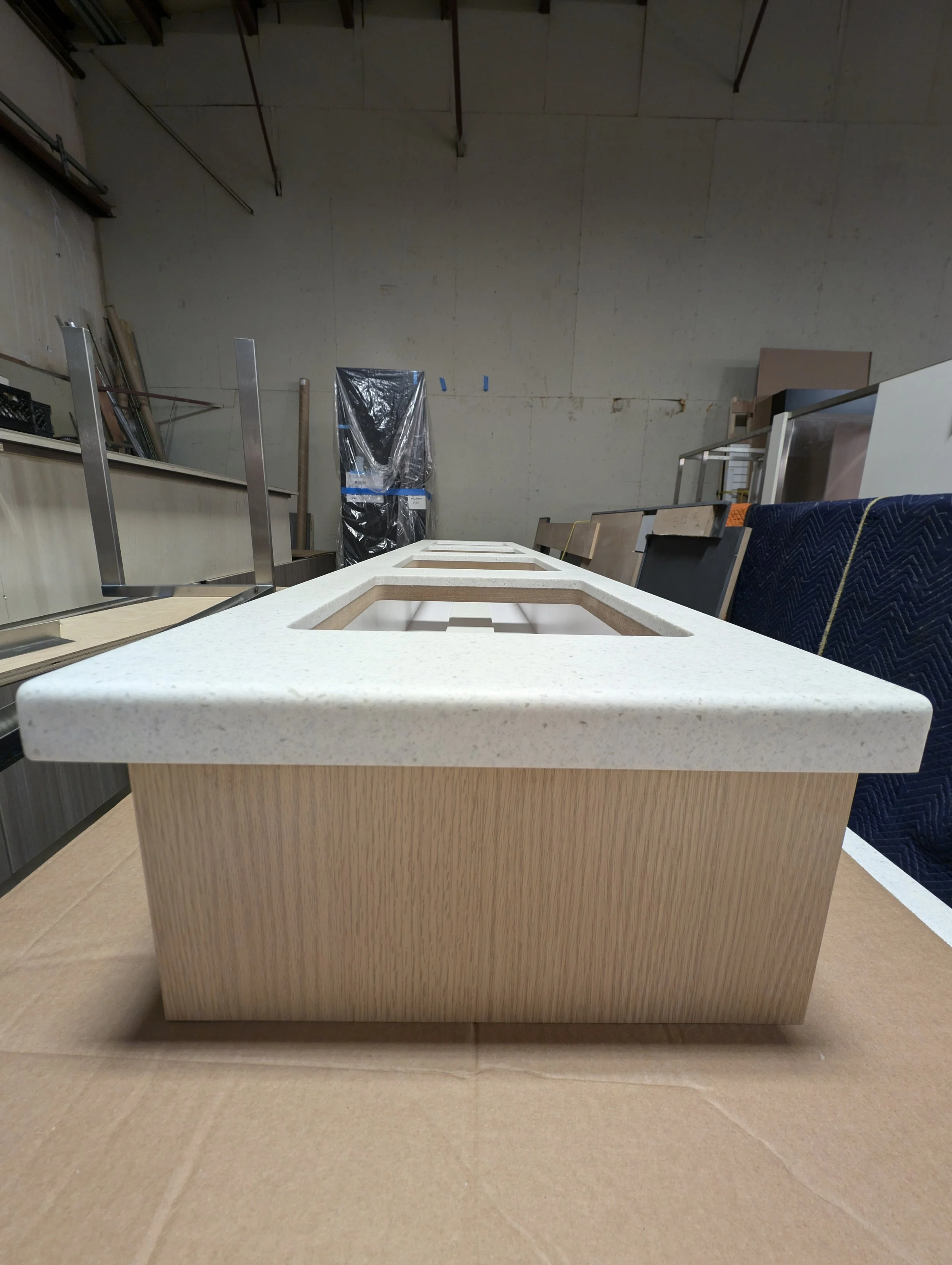 Wooden cabinet with a white speckled countertop in a workshop.