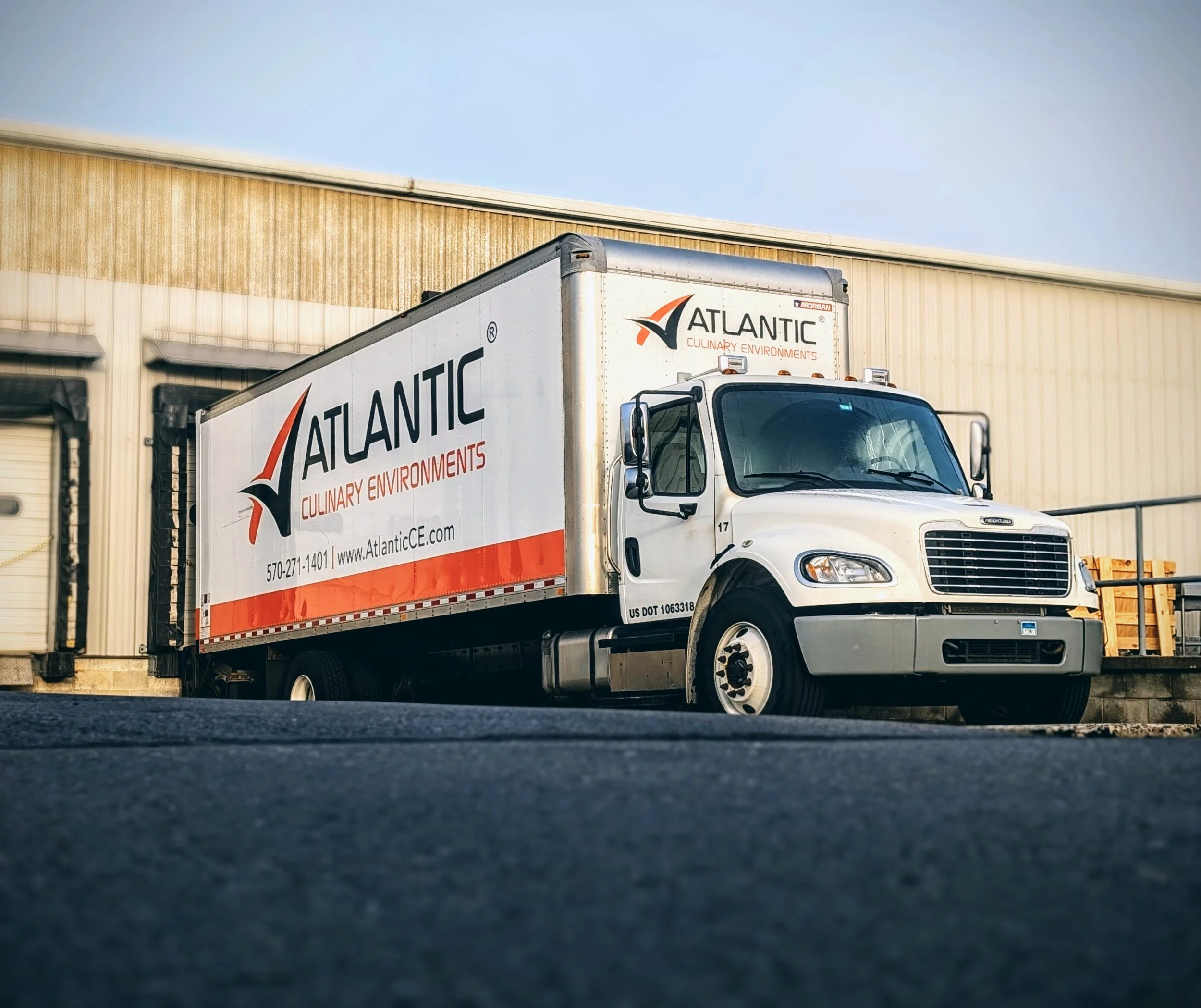 White delivery truck with Atlantic logo and text parked outside a warehouse.