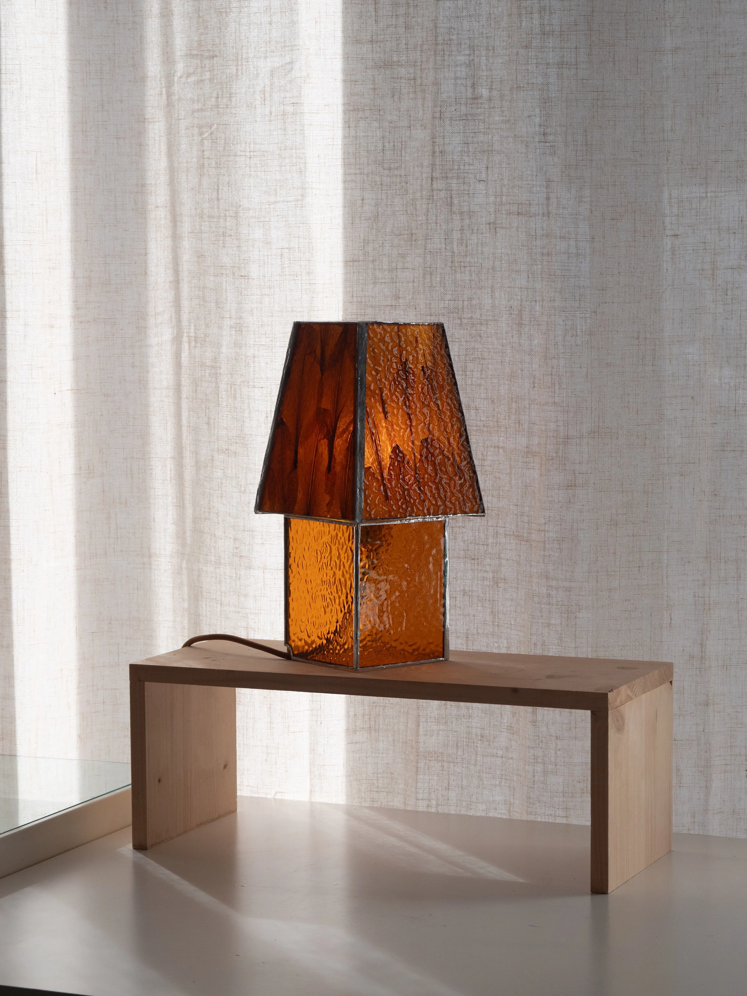 LAMPE AURORE, faite de vitrail et de p&eacute;tales de lys. 

Une aurore ne dure que quelques minutes, une fleur quelques semaines. Nous avons voulu prolonger ces instants &eacute;ph&eacute;m&egrave;res et leur donner corps dans la lumi&egrave;re.

C