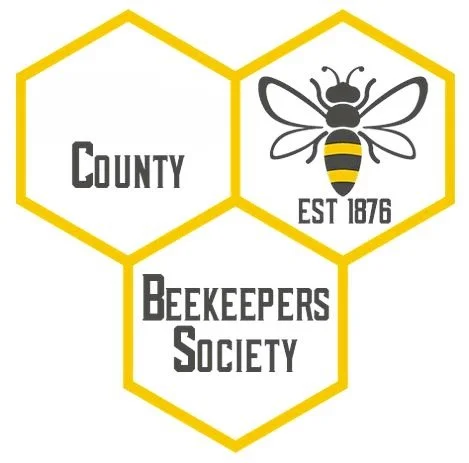 Logo with three yellow-outlined hexagons, a bee, and text reading 'County Beekeepers Society EST 1876'.