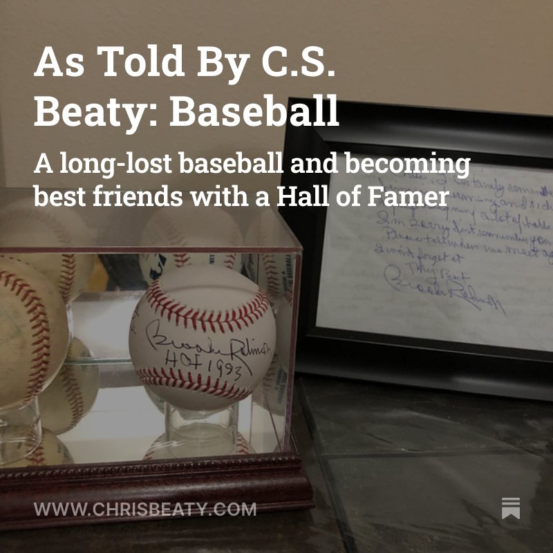 A baseball signed by Buck Reams with the inscription 'HOF 1952', displayed in a glass case, and a handwritten note or letter placed beside it.