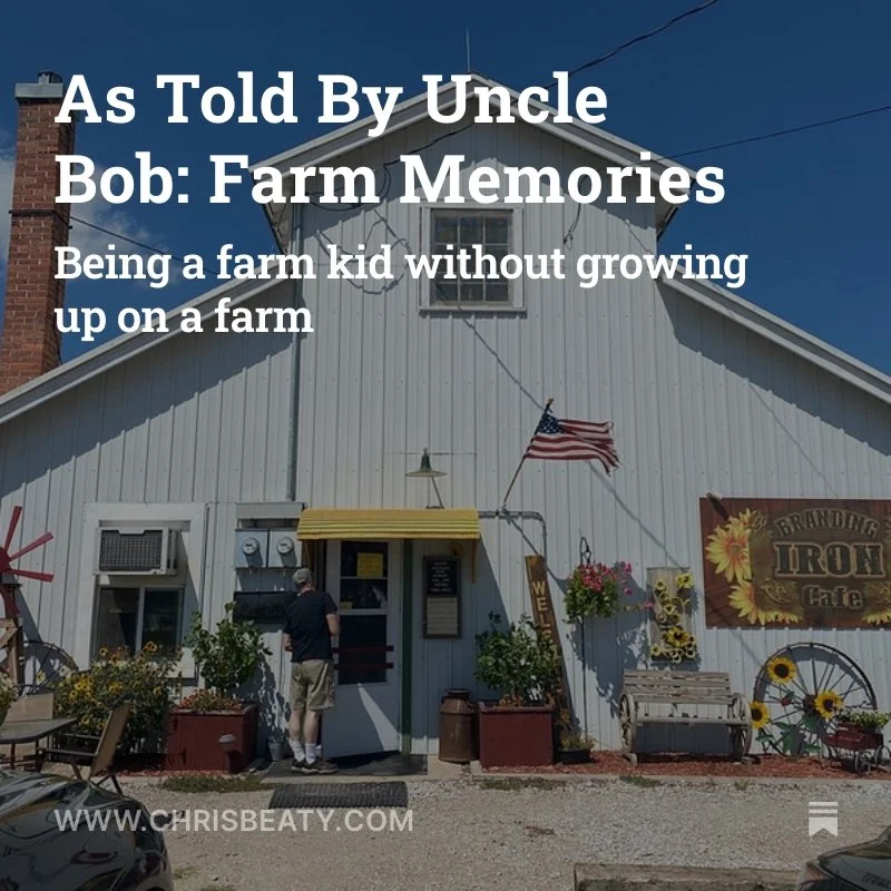 White farmhouse-style building with an American flag, sunflower decorations, and a sign reading 'Branding Iron Cafe' against a blue sky.