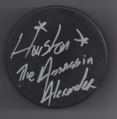 A round black button with white handwritten text that reads 'Houston & The Assassin in Alexandria'.