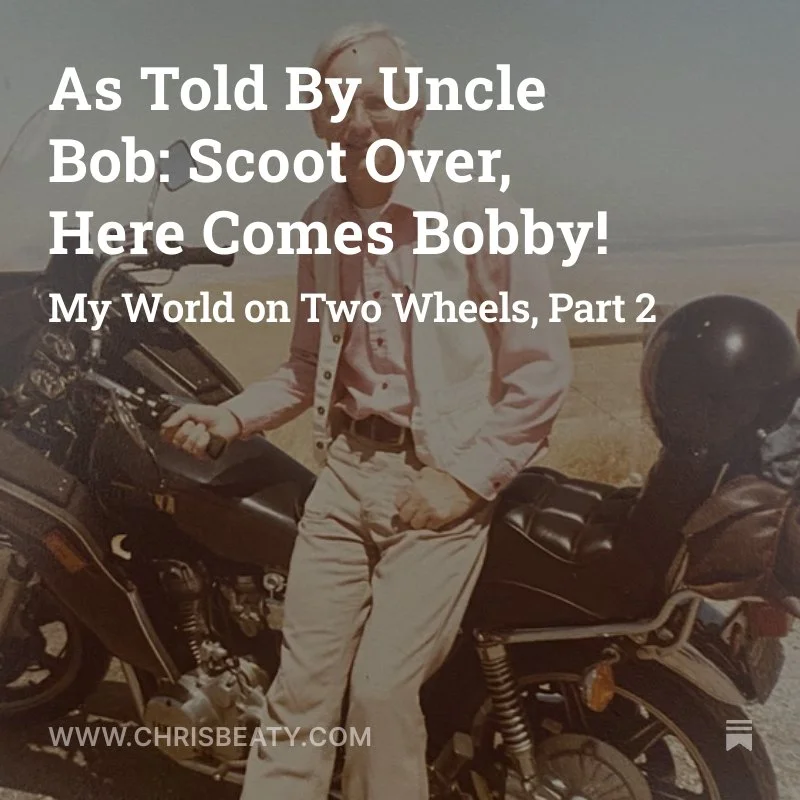 An older man with white hair, glasses, wearing a light pink shirt, beige pants, and a white jacket, standing beside a black motorcycle on a daytime outdoor setting with a clear sky.