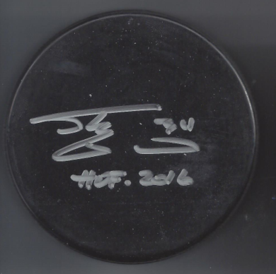 A black hockey puck with white handwritten text and signature, including the date '11.27.2016'.