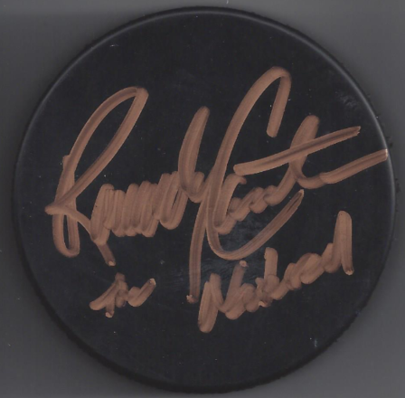 A black circular puck with a signature written in gold marker that reads "Lindsey Graham".