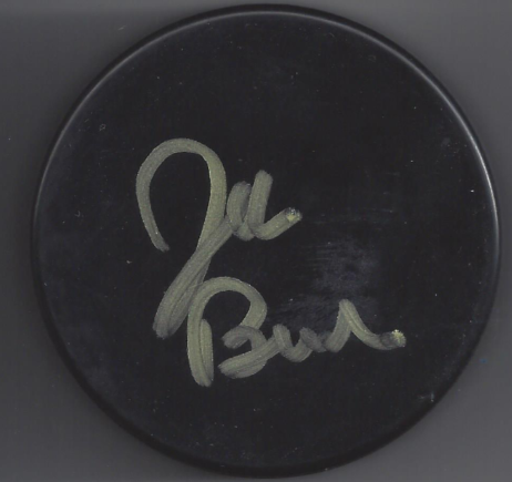 Close-up of a black hockey puck with a silver signature written on it.
