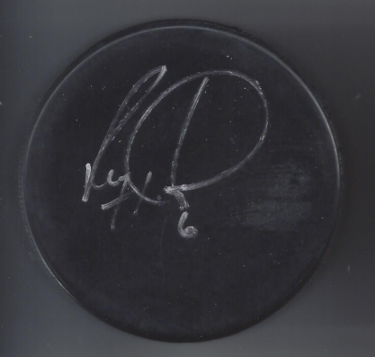 Close-up of a black circular object with a white handwritten signature or inscription on it.