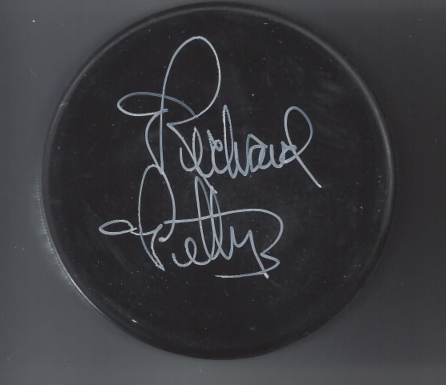 Black hockey puck with white signature on it.