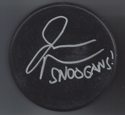 A black circular object with white handwriting that says 'SNOGANS!' and a signature or stylized signature above it.