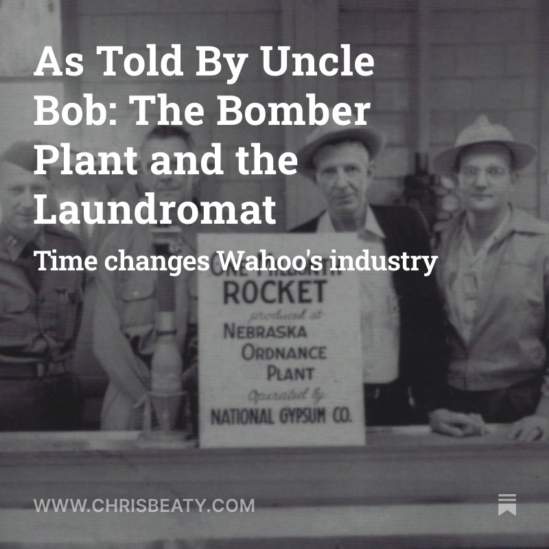 Black and white photograph showing four men standing behind a sign that reads: 'ROCKET produced at NEBRASKA ORDNANCE PLANT operated by NATIONAL GYPSUM CO.' The men are wearing hats and clothing typical of the early to mid-20th century.