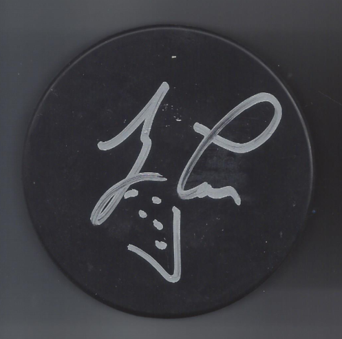 Autographed black hockey puck with a silver marker signature.