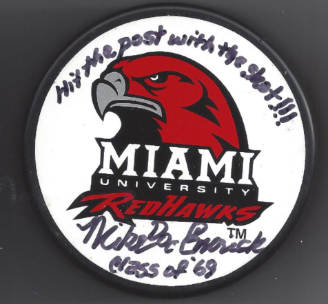 A Miami University RedHawks hockey puck featuring the team's red hawk logo, the Miami University logo, the word 'RedHawks' in red, a handwritten message, and the signature of someone named Nicole Graw at the bottom.