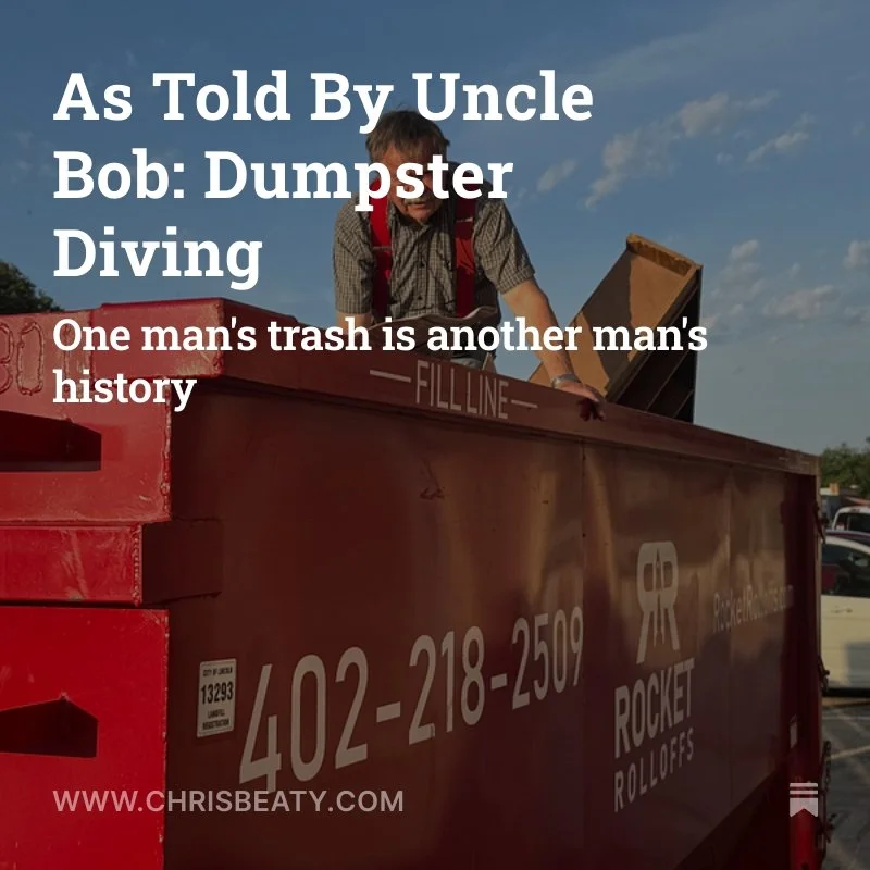 A man standing on a red dumpster with the label 'ROCKET ROLLOFFS' and the number '402-218-2509.' He is wearing glasses, a checkered shirt, and suspenders, and appears to be placing or retrieving an item from the dumpster against a background of a blue sky with clouds.