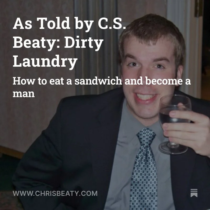 A man in a suit holding a glass of red wine, smiling at the camera.