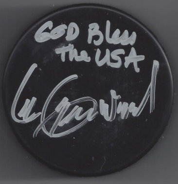 A black circular item with handwritten white text reading "God Bless the USA" and a signature below.