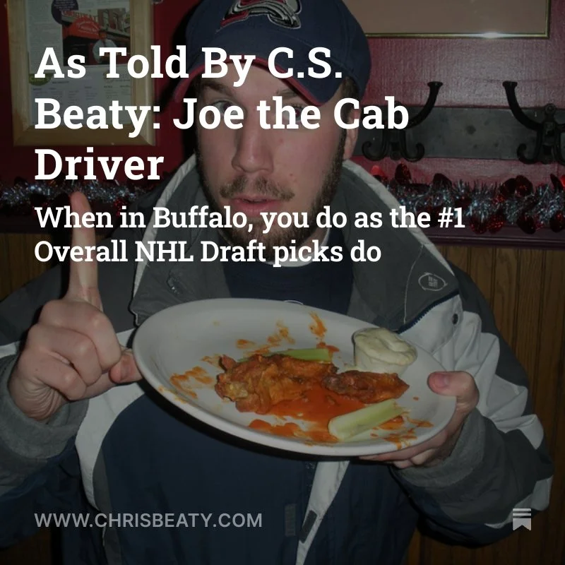A man in a Seattle Seahawks hat holding a plate of Buffalo chicken wings with celery and ranch dressing, giving a thumbs up in a restaurant decorated for the holidays.