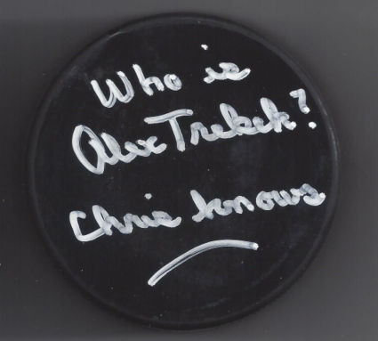 A black circular badge with white handwritten text that says, 'Who is Alex Trubeck?'.